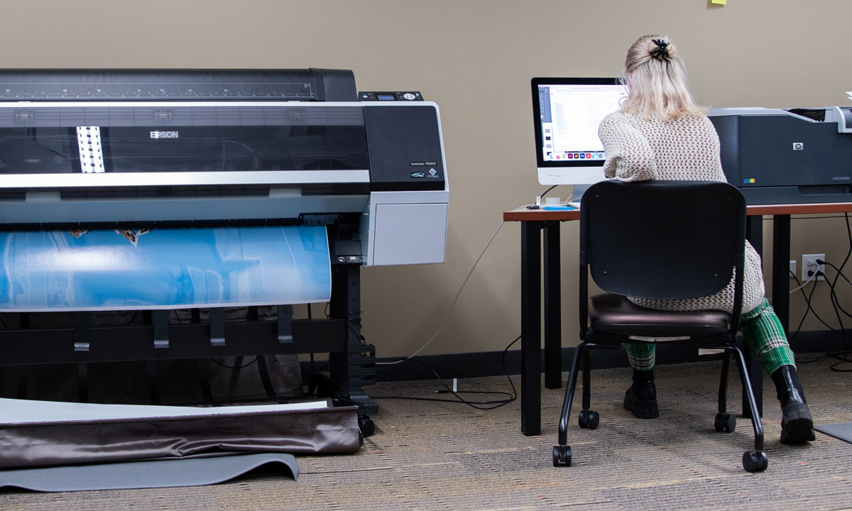student working next to a large scale printer