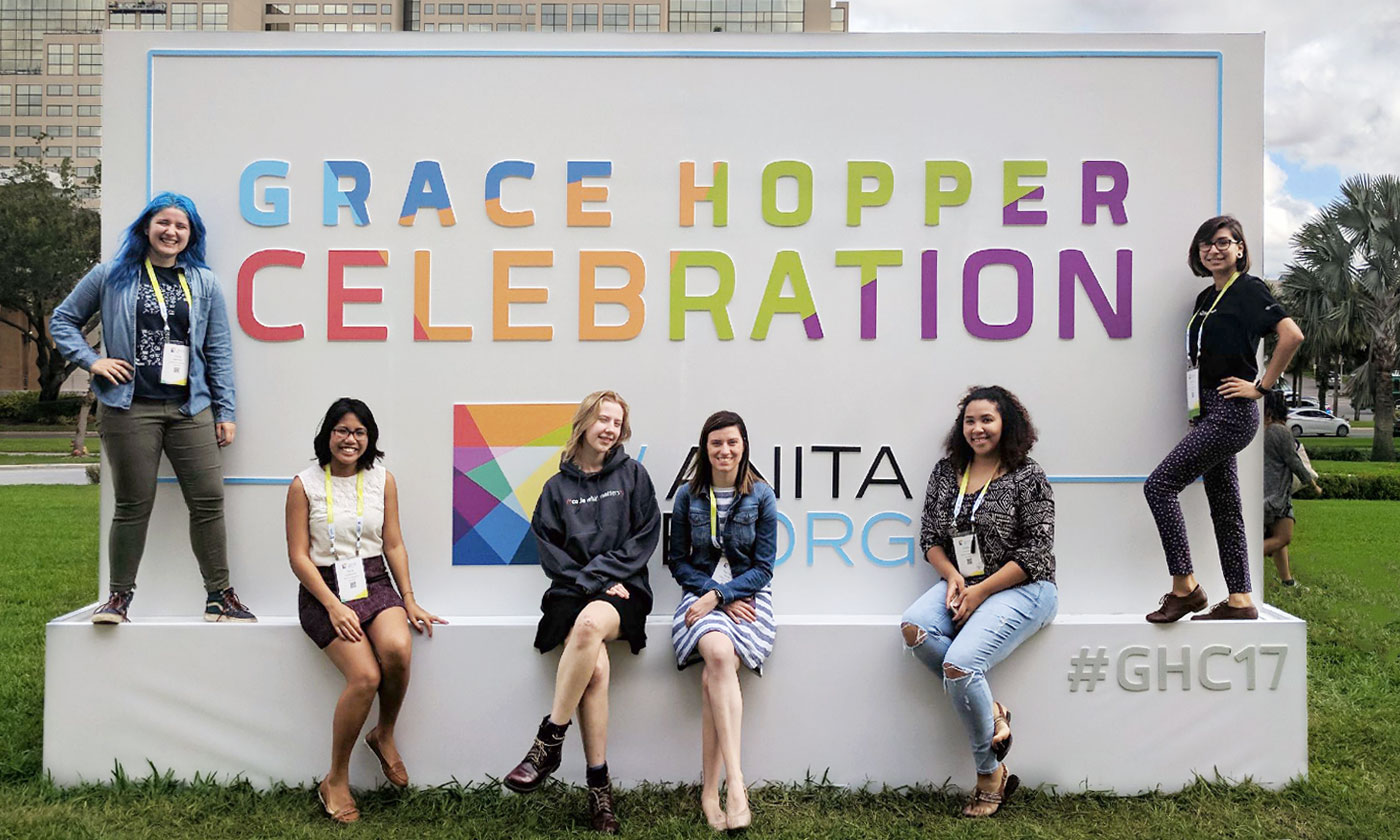 six female students posing infront of a huge Grace Hopper Celebration sign