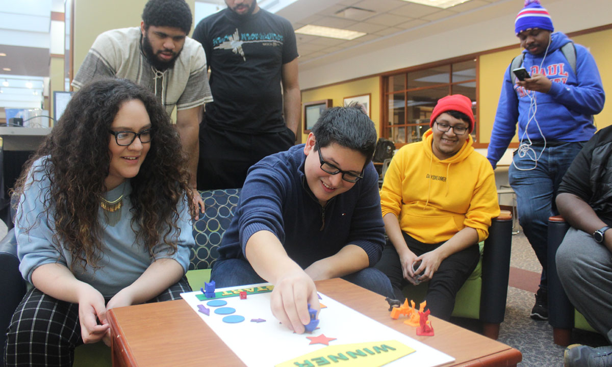 students huddled around playing a board game