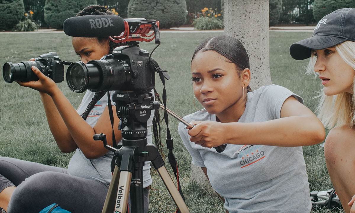 2 high school students using professional film equipment outside
