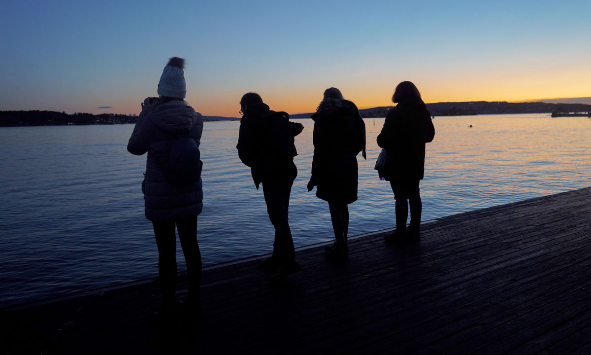 four students near water during sunset